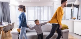 Small boy pulling his parents in the living room who are about to get a divorce.