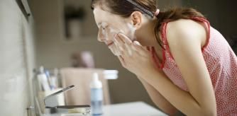 Una joven lavándose la cara.