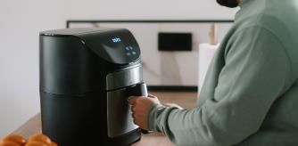 Una persona cocinando con una freidora de aire.