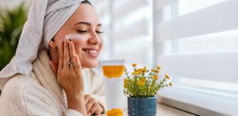 Una mujer aplicándose una mascarilla nocturna en el rostro.