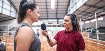 Una joven periodista deportiva entrevistando a una jugadora de baloncesto.