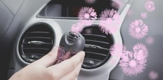 Una mujer poniendo un ambientador en el coche