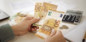 Una mujer contando billetes con una calculadora en la mesa