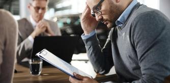 Un hombre lee el contrato de compra de un coche en el concesionario