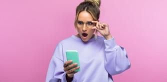 Una mujer mirando el móvil con cara de sorpresa