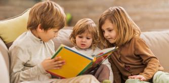 Tres niños leyendo un libro