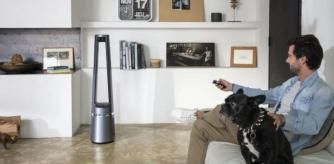 Un hombre con un perro manejando un ventilador sin aspas en su salón