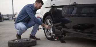 Un hombre cambiando la rueda del coche