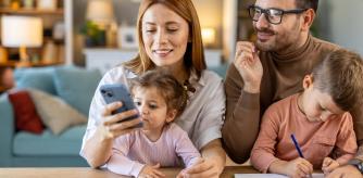 Una familia mirando el móvil mientras el niño escribe en una libreta