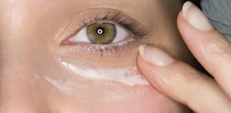 Una mujer se aplica crema antiojeras