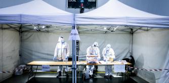 El pasado 14-F hubo elecciones autonomicas catalanas a pesar de la tercera ola por la pandemia coronavirus. Tres personas vestidas con EPIs en la mesa electoral del polideportivo la Sagrera, Barcelona