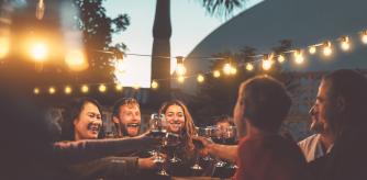Cena de verano con amigos con una cálida iluminación de una guirnalda de bombillas.