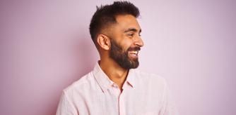 Hombre con camisa contra fondo rosado.