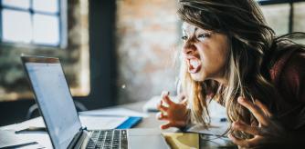 Angry freelance worker feeling displeased after reading an e-mail on a computer.