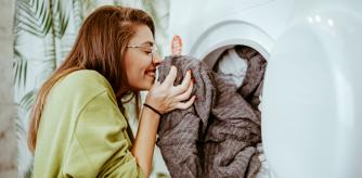 Young woman takes laundry out of the washing machine