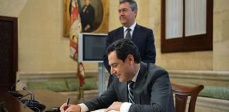 Moreno Bonilla escribe en el libro de honor del Ayuntamiento de Sevilla con Juan Espadas al fondo (Junta de Andalucía)