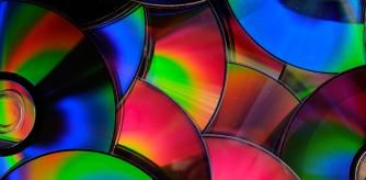 Group of old CD DVD compact optical disk storage medium with dust and scratches. Rainbow spectrum of iridescent colors