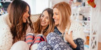 Tres amigas en pijama envueltas en una manta.