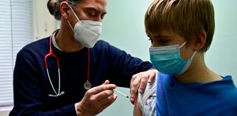 Paediatrician medic Jakob Maske vaccinates an 11 year-old boy in his office in Berlin on December 14, 2021, at the start of COVID-19 vaccination campaign for children under 12 years in Germany. (Photo by Tobias SCHWARZ / AFP)