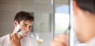Hombre afeitándose delante de un espejo