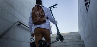 Hombre con patinete sube unas escaleras
