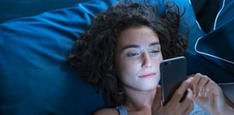 Una mujer joven consulta su móvil desde la cama