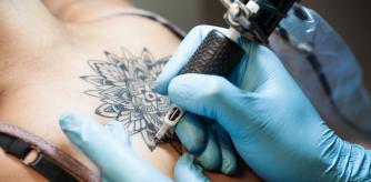 Tattoo artist at work on a girl's backpiece