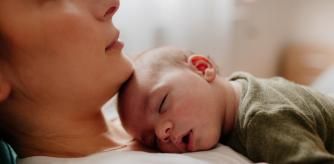 Photo of a young mother holding her newborn baby, while putting him to sleep