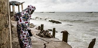 A woman looks down a newly formed crack in the walk way which leads to the Mosque in Bargny on September 18, 2020. - Fishing villages like Bargny have been fighting the rising seas for decades, hundreds of houses have been lost and families displaced. Through the months of July to September, peaking at the equinox, coastal towns like Bargny must brace for the worst, tides are at their highest, rising every year, storms are more frequent, battering the coastline which speeds up the erosion. (Photo by JOHN WESSELS / AFP)