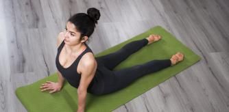 Young woman demonstrates upward facing dog yoga pose at home