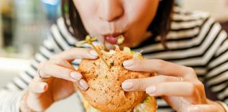 Woman eating a hamburger in modern fastfood cafe, lunch concept