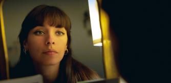 Beautiful young woman looking herself in the mirror