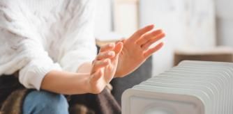 Una persona ante un calefactor eléctrico.
