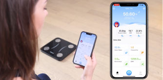 Una mujer mirando sus resultados de la báscula inteligente con el dispositivo móbil