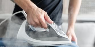 Una persona planchando la ropa con una plancha de vapor.
