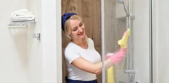 Una mujer limpiando la mampara de la ducha