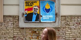 A woman walks by political themed posters by artist Patricio Handl, in Vienna, Austria, Thursday, Sept. 26, 2024, ahead of the country's national election that will take place on Sept. 29. (AP Photo/Andreea Alexandru)