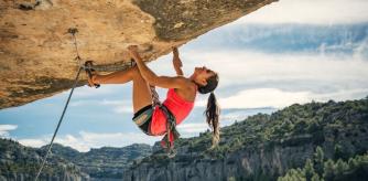 Una escaladora bien equipada sube bocabajo por una roca