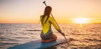 Una chica navega en una tabla de paddlesurf mientras disfruta del atardecer