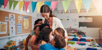 Unos jóvenes alumnos abrazan a su profesora antes de las vacaciones de verano