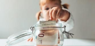 Una niña guardando billetes de euro en un pote de cristal