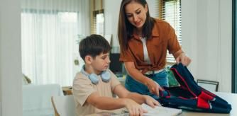 Un niño y su madre preparan la mochila antes de ir a clase