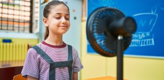 Una niña se refresca con un mini ventilador