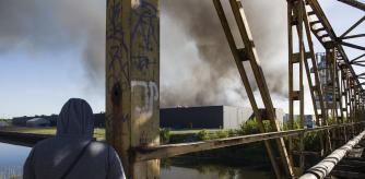 WARSAW, MASOVIAN VOIVODESHIP, POLAND - 2024/05/12: A person looks at the burning Marywilska 44 shopping center in Warsaw. A massive fire broke out at the Marywilska 44 shopping center in Warsaw's Biaoleka district. According to the State Fire Service, there are 50 fire brigades on site, with a total of nearly 300 firefighters working there, including from the chemical unit. Water is drawn from a nearby canal to extinguish the fire. About 1400 shops are completely burnt down so far. Residents of Warsaw and the surrounding area received a government security center alert, urging them to stay at home and close their windows. (Photo by Attila Husejnow/SOPA Images/LightRocket via Getty Images)