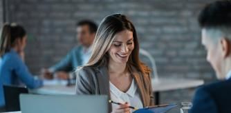Young happy businesswoman reading reports while going through paperwork and working with a colleague in the office.