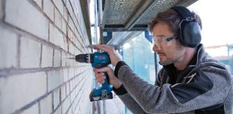 Un hombre taladrando una pared de ladrillos
