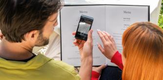 Una pareja traduce la carta de un restaurante con el Traductor Q1 antes de pedir