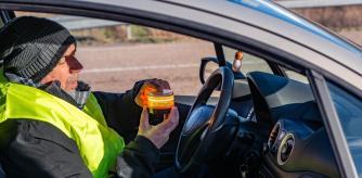 Un hombre enciende su baliza V16 antes de ubicarla en la parte superior del coche