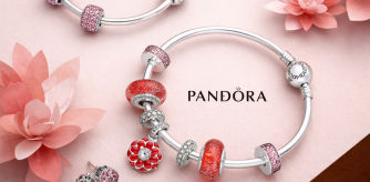 Pulseras Pandora con charms icónicos en tonos rosas y rojos, fotografía de producto sobre fondo floral