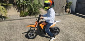 Mi sobrino muy contento con su bicicleta eléctrica en el jardín de su casa